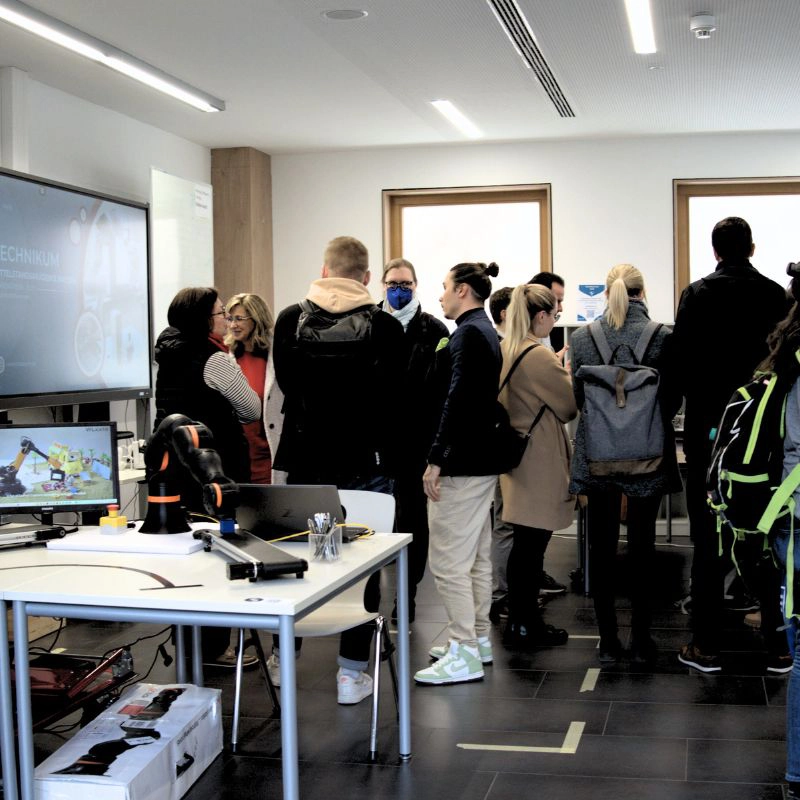 Gruppe von Menschen im Technikum beim offenen Austausch über moderne Technologien und Bildungskonzepte.