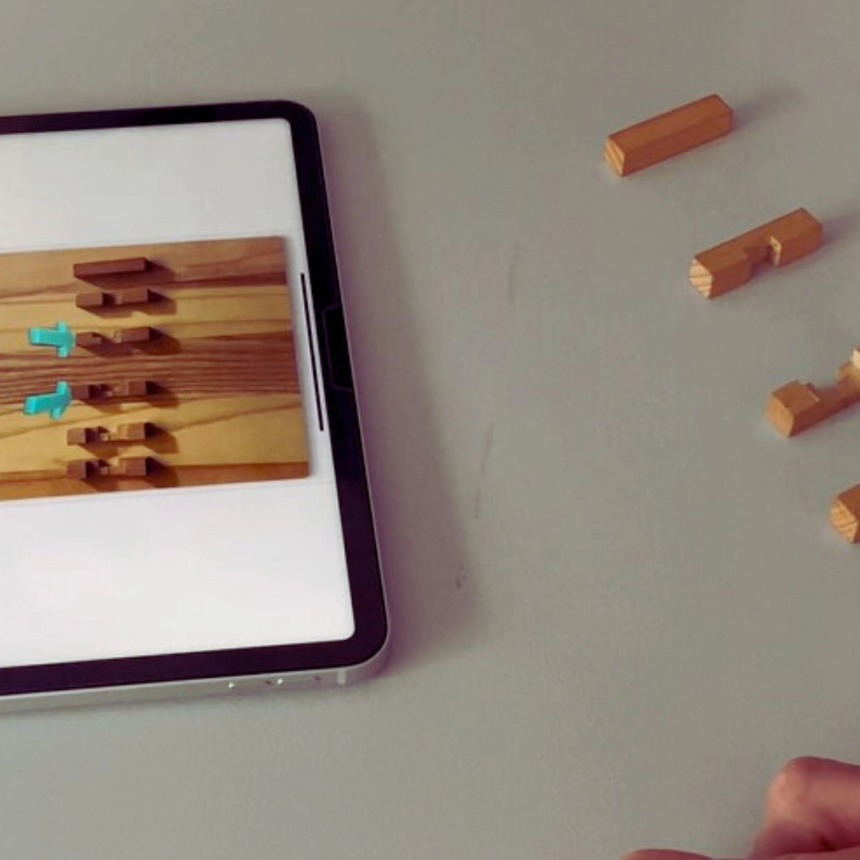 Tablet mit digitalen Holzverbindungen und reale Holzelemente als Übung zur Problemlösung in einem Empowerment-Workshop für Mitarbeiter.
